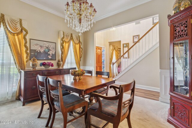 dining space with ornamental molding, an inviting chandelier, and light colored carpet