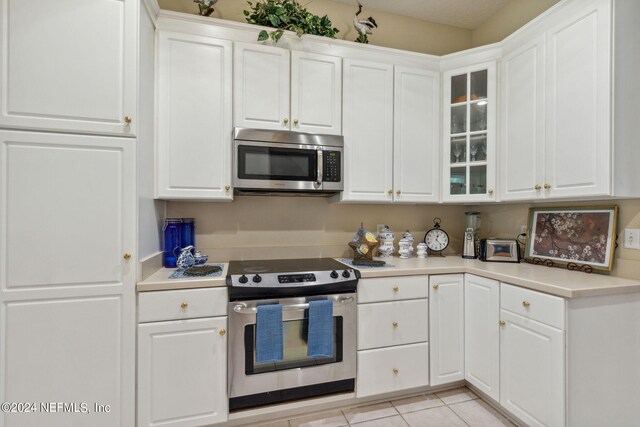 kitchen featuring light tile patterned floors, white cabinets, and stainless steel appliances