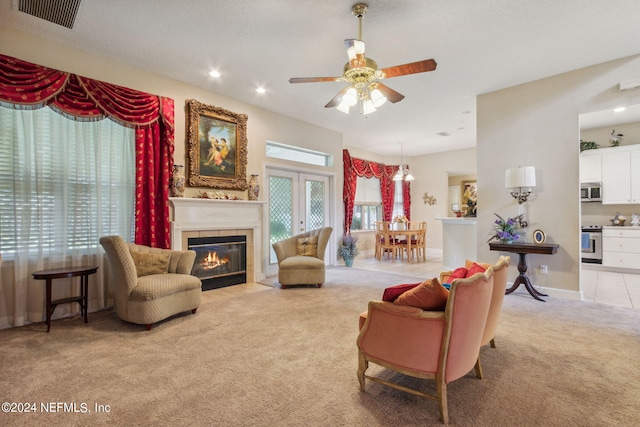 carpeted living room featuring ceiling fan, a fireplace, and french doors