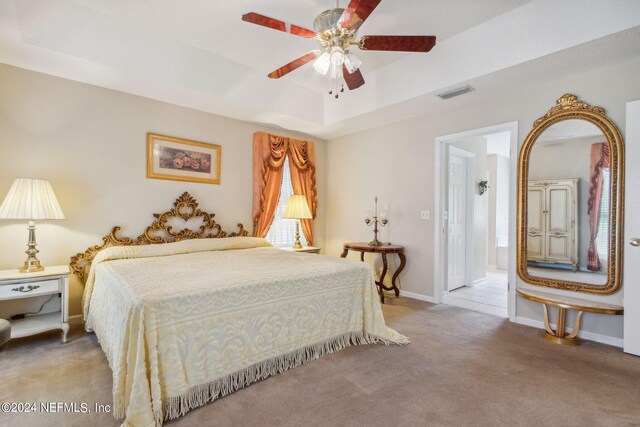 bedroom with carpet flooring, ceiling fan, and a tray ceiling