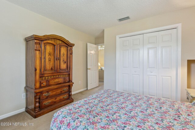 carpeted bedroom featuring a textured ceiling and a closet