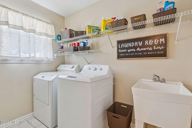 laundry room featuring light tile patterned floors, washing machine and clothes dryer, and sink