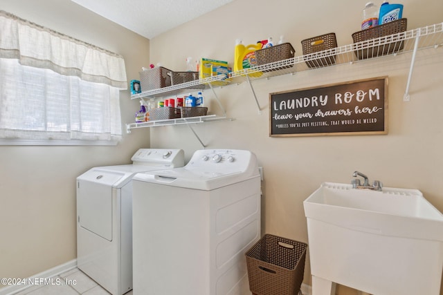 laundry area with sink, washing machine and dryer, and light tile patterned floors