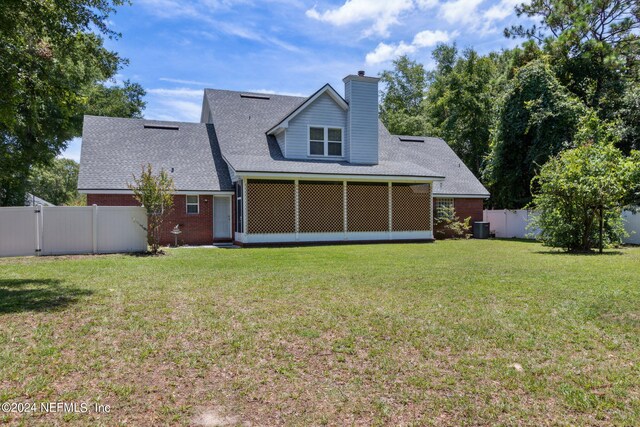 back of house featuring a sunroom and a lawn