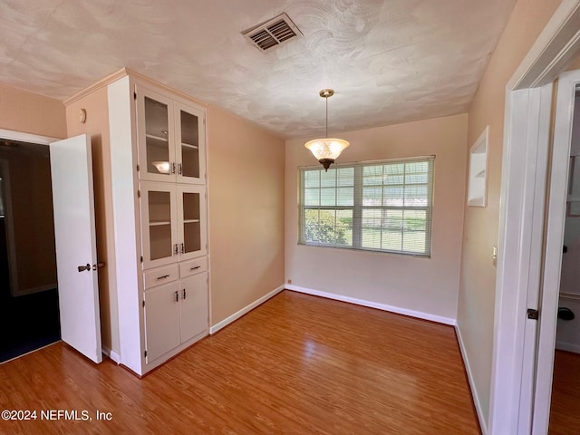 unfurnished dining area with hardwood / wood-style floors and a textured ceiling