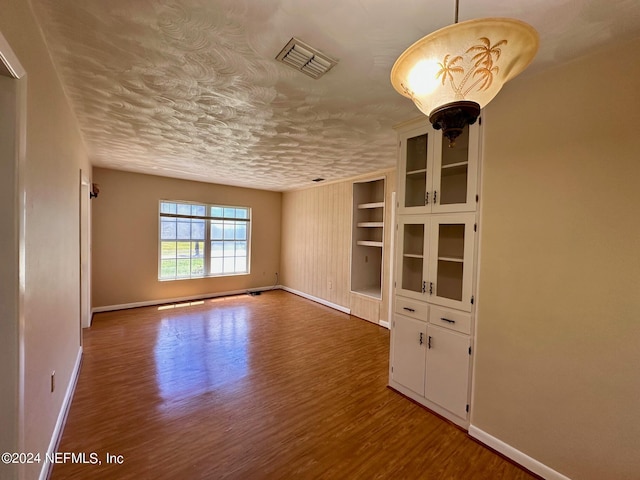 unfurnished living room featuring built in features and hardwood / wood-style flooring