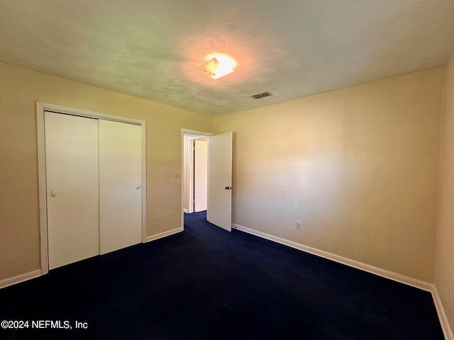 unfurnished bedroom with a closet and dark colored carpet