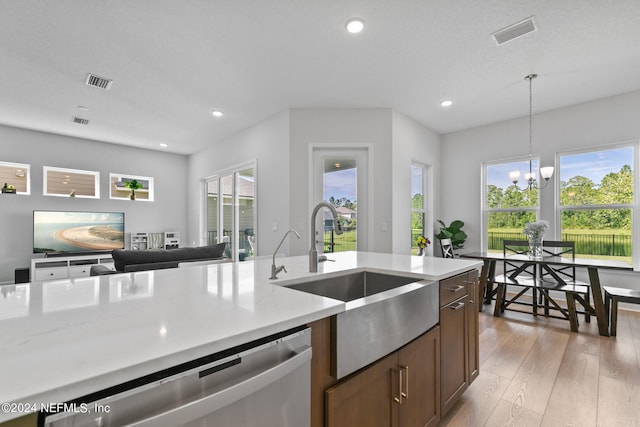 kitchen with light hardwood / wood-style flooring, a chandelier, stainless steel dishwasher, hanging light fixtures, and sink