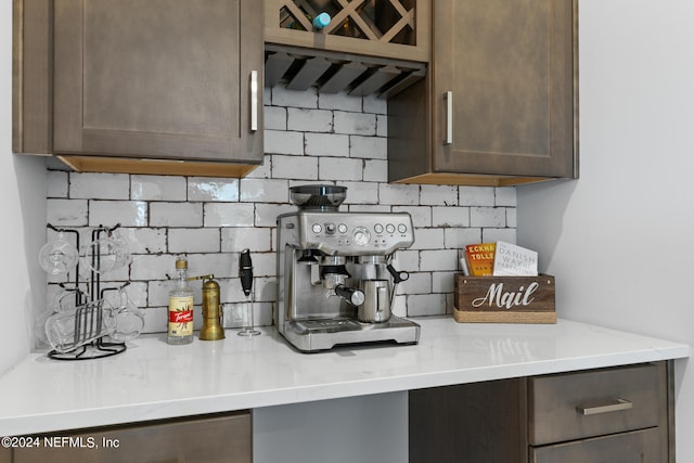 kitchen with dark brown cabinetry, light stone counters, and tasteful backsplash