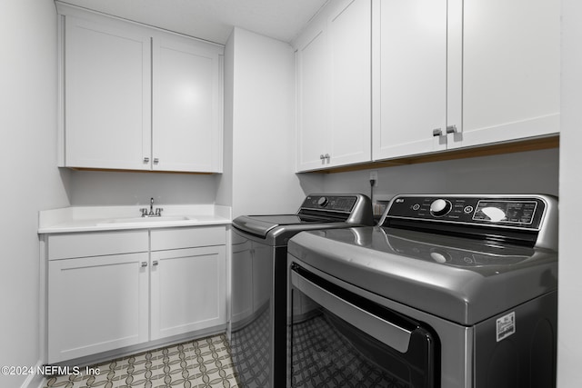 laundry area featuring light tile patterned flooring, washing machine and clothes dryer, cabinets, and sink