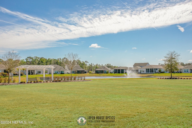 view of front of home with a pergola, a water view, and a front lawn