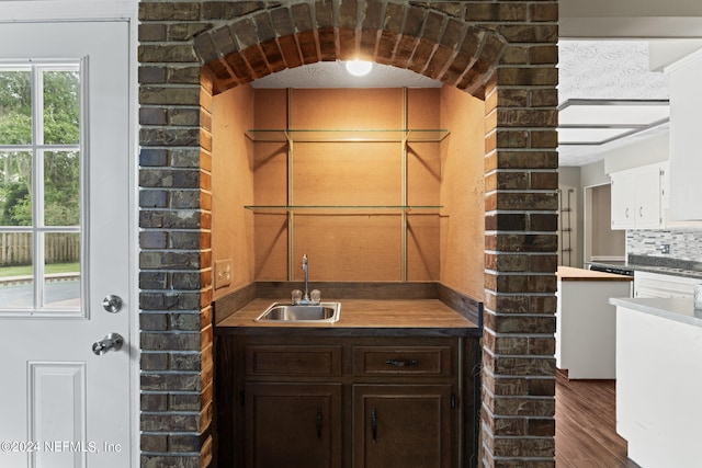 bar with backsplash, sink, dark hardwood / wood-style floors, white cabinetry, and dark brown cabinetry