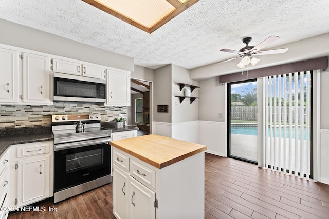 kitchen with decorative backsplash, white cabinetry, a kitchen island, and stainless steel appliances