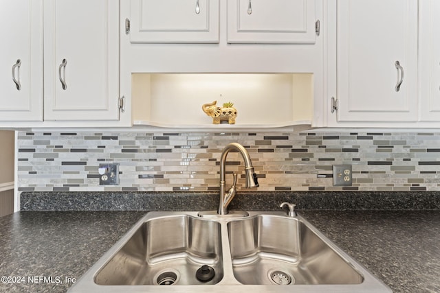 kitchen featuring white cabinets, decorative backsplash, dark stone countertops, and sink