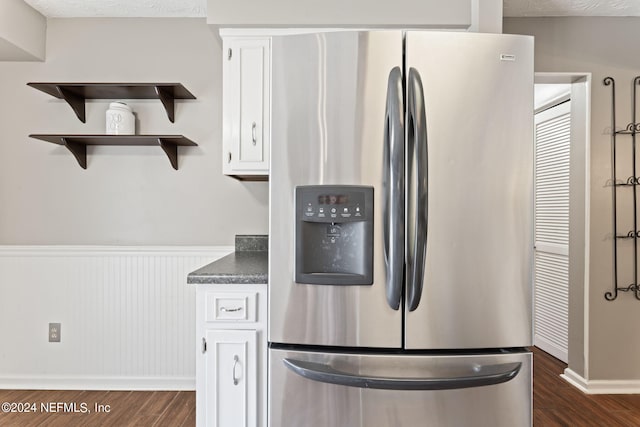 kitchen featuring stainless steel fridge, dark hardwood / wood-style floors, and white cabinetry