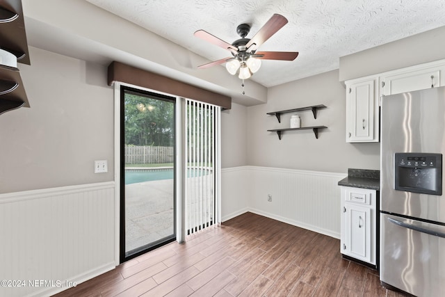 kitchen with white cabinets, stainless steel fridge, a textured ceiling, and ceiling fan