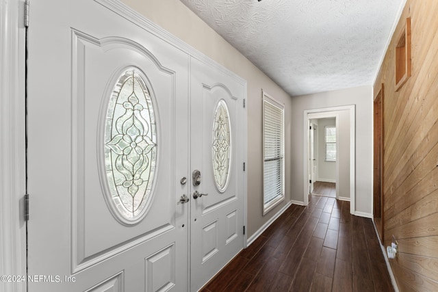 entryway featuring wood walls, a textured ceiling, and dark wood-type flooring