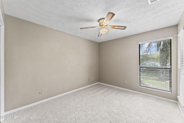 carpeted spare room with a textured ceiling, ceiling fan, and a healthy amount of sunlight