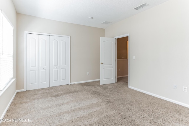 unfurnished bedroom with a closet, multiple windows, and light colored carpet