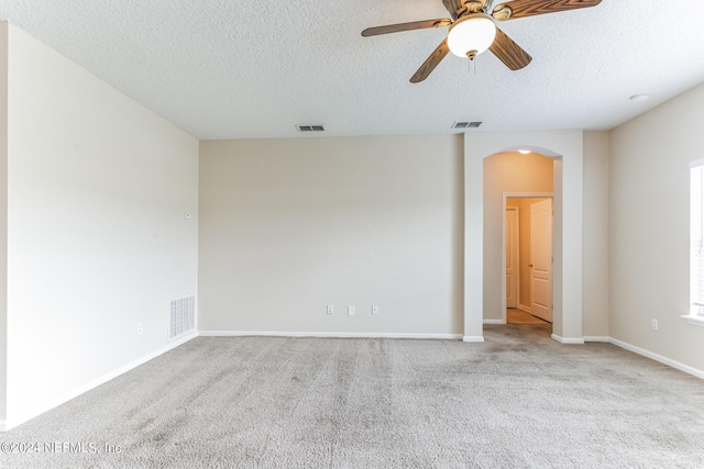 spare room featuring light colored carpet, ceiling fan, and a textured ceiling