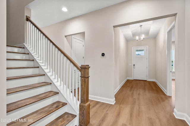 entrance foyer with stairs, an inviting chandelier, light wood-style flooring, and baseboards