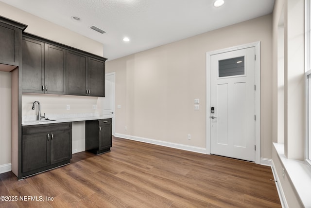 kitchen featuring visible vents, wood finished floors, light countertops, and a sink