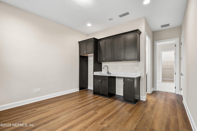 kitchen with visible vents, baseboards, light countertops, wood finished floors, and a sink