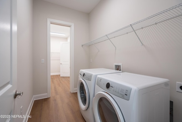 laundry room featuring light wood-style floors, baseboards, separate washer and dryer, and laundry area