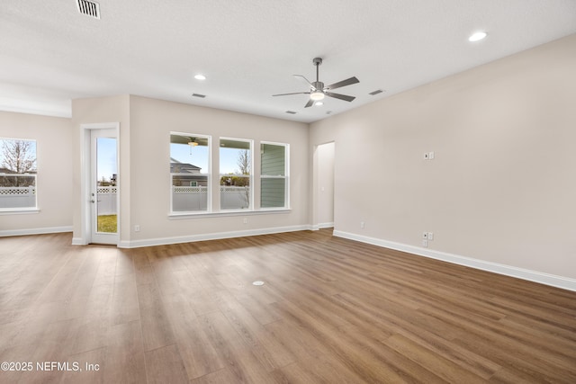 unfurnished living room with ceiling fan, visible vents, baseboards, and wood finished floors