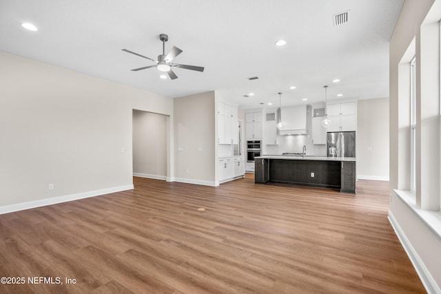 unfurnished living room with light wood finished floors, visible vents, baseboards, ceiling fan, and recessed lighting