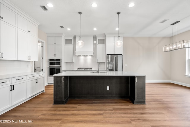 kitchen featuring a sink, stainless steel appliances, custom exhaust hood, and visible vents