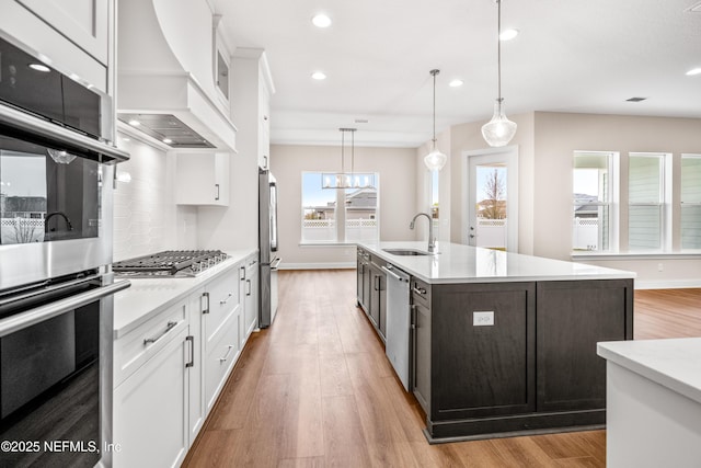 kitchen with custom range hood, a sink, stainless steel appliances, white cabinets, and light countertops