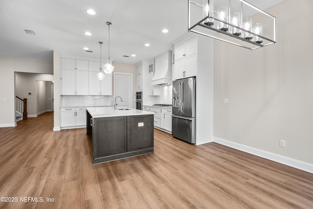 kitchen featuring visible vents, premium range hood, a sink, light countertops, and appliances with stainless steel finishes