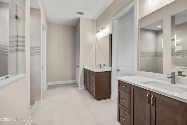 bathroom featuring two vanities, walk in shower, and a sink