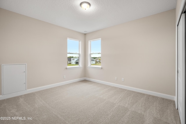 carpeted spare room featuring baseboards and a textured ceiling