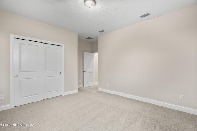 unfurnished bedroom featuring visible vents, baseboards, carpet flooring, a closet, and a textured ceiling