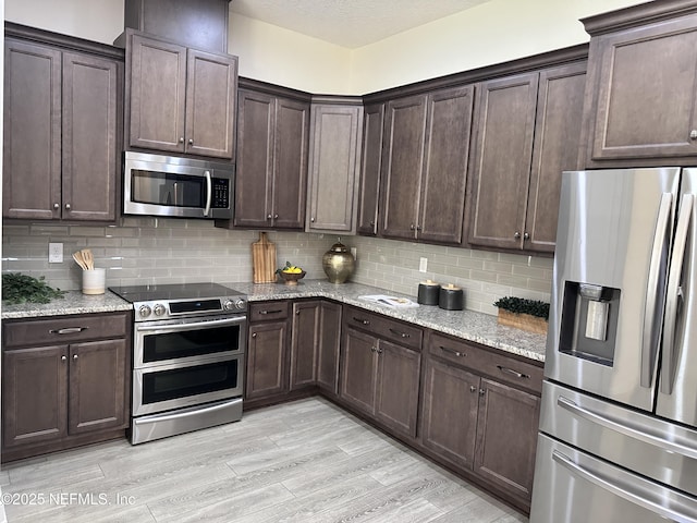 95014 Brookhill Pl, Fernandina Beach, FL 32034 - kitchen featuring stainless steel appliances, dark brown cabinets, decorative backsplash, and light stone counters