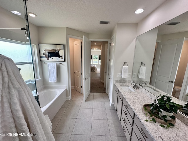 95014 Brookhill Pl, Fernandina Beach, FL 32034 - ensuite bathroom featuring a bath, double vanity, tile patterned flooring, a textured ceiling, and recessed lighting