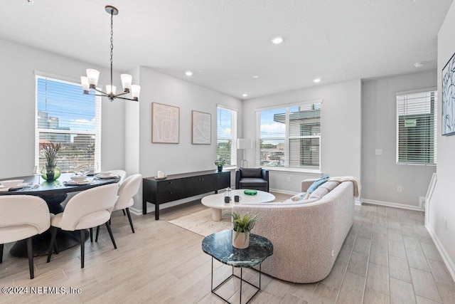 living room with light wood-type flooring, an inviting chandelier, and a wealth of natural light