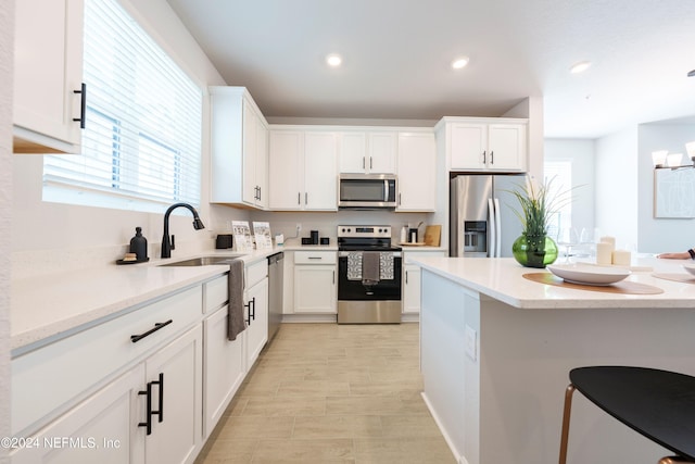 kitchen featuring white cabinetry, sink, light stone counters, and appliances with stainless steel finishes