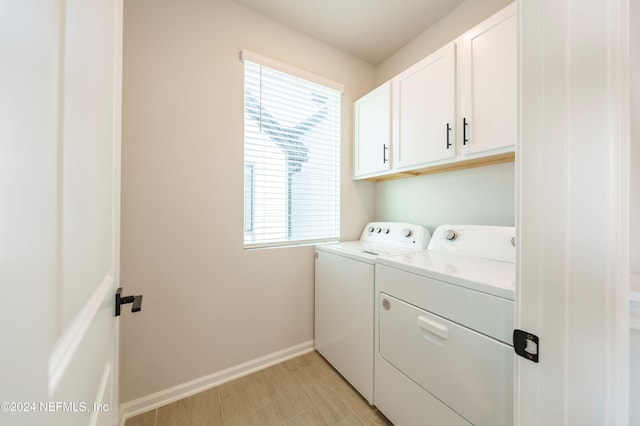 clothes washing area featuring cabinets, a wealth of natural light, and washing machine and clothes dryer