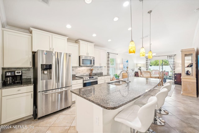 kitchen featuring decorative light fixtures, a kitchen island with sink, sink, and appliances with stainless steel finishes