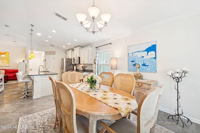 dining space featuring a notable chandelier, crown molding, sink, and vaulted ceiling