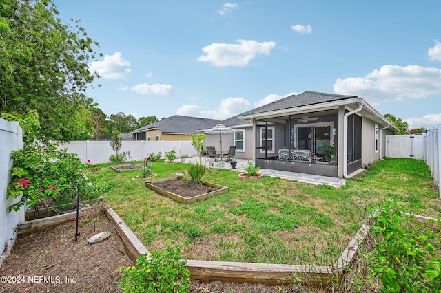 back of property featuring a lawn, a patio area, and a sunroom