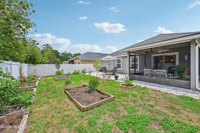 view of yard featuring a sunroom, ceiling fan, and a patio