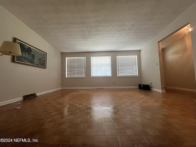 empty room featuring dark parquet floors and a textured ceiling