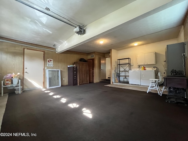 garage with a garage door opener, independent washer and dryer, and wood walls