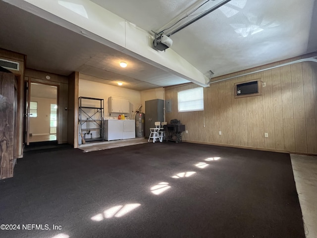 garage featuring washing machine and dryer, wood walls, and a garage door opener