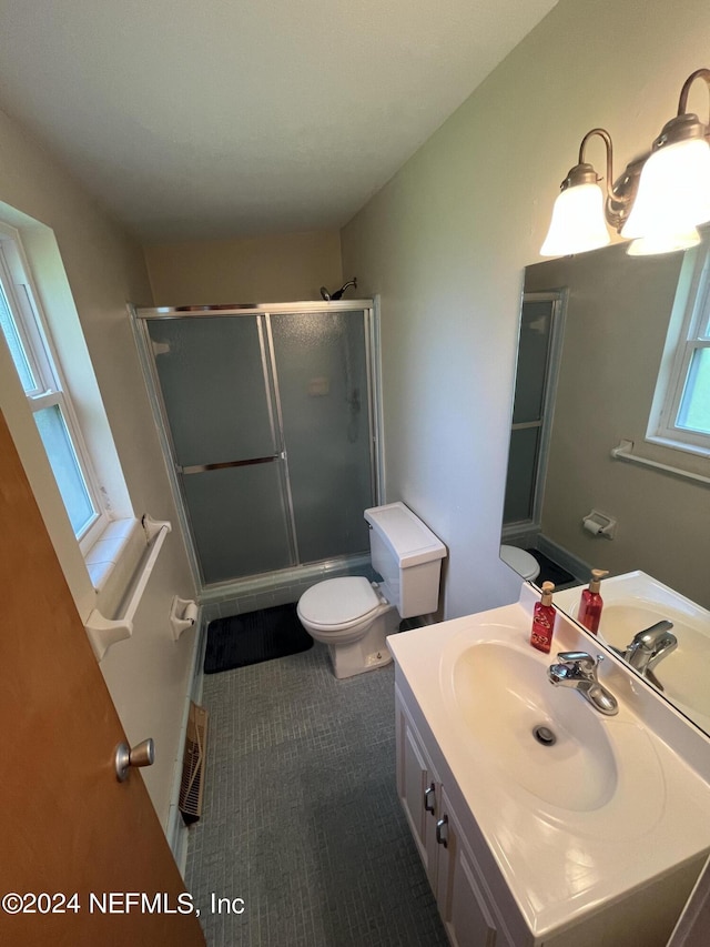 bathroom featuring a shower with shower door, toilet, and vanity