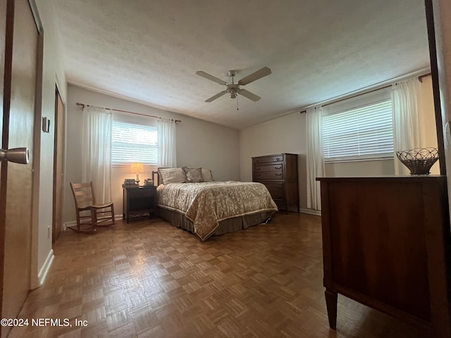 bedroom with ceiling fan, a textured ceiling, and parquet flooring